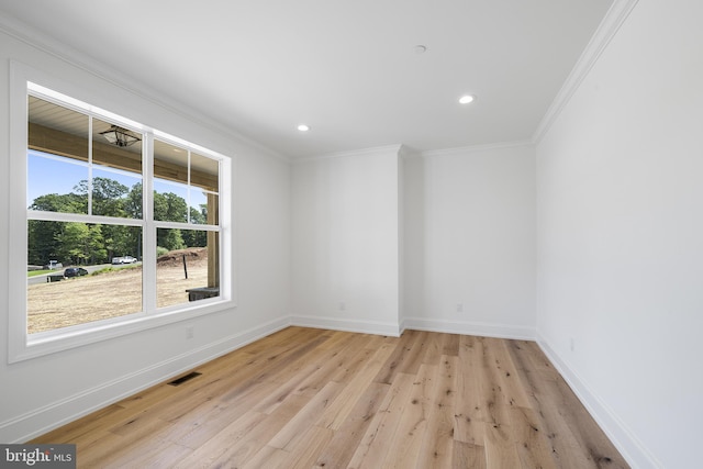 empty room featuring plenty of natural light, light wood-type flooring, and crown molding