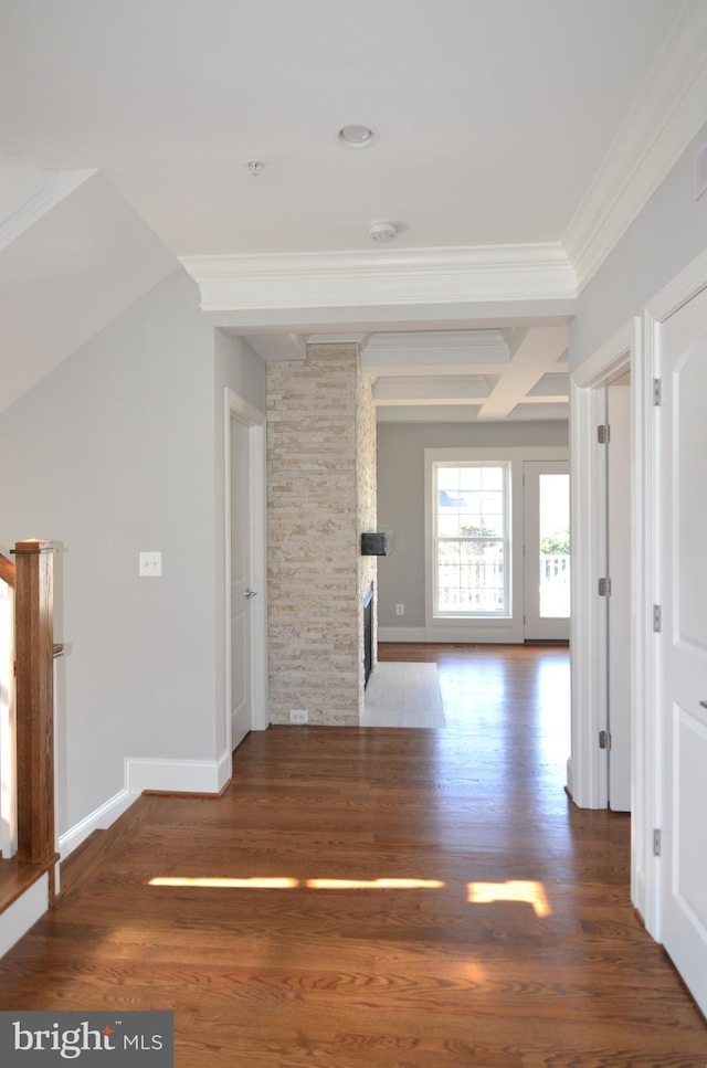 interior space featuring coffered ceiling, beam ceiling, ornamental molding, a stone fireplace, and dark wood-type flooring