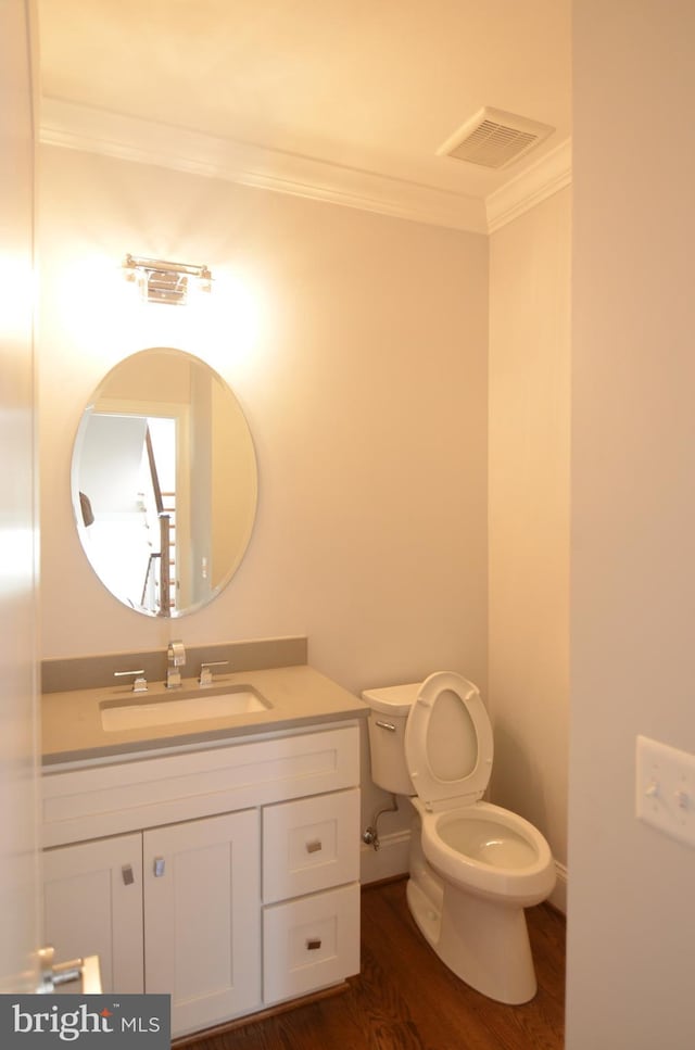 bathroom with ornamental molding, toilet, hardwood / wood-style flooring, and vanity