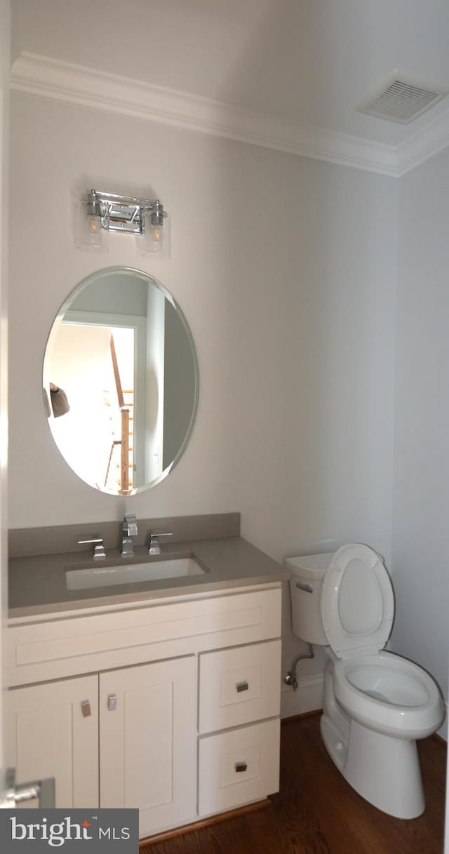 bathroom with vanity, crown molding, and toilet