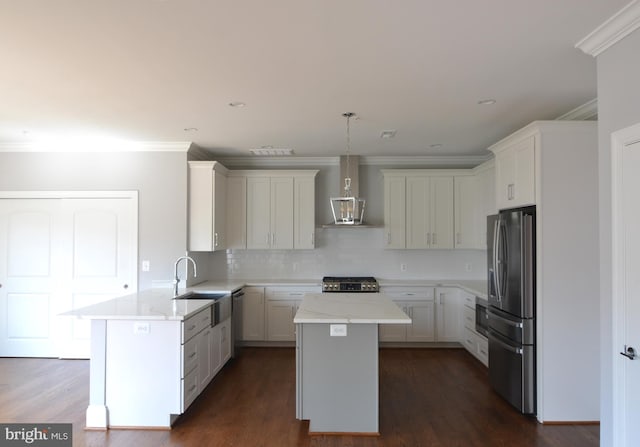 kitchen featuring appliances with stainless steel finishes, wall chimney range hood, a kitchen island, dark wood-type flooring, and sink