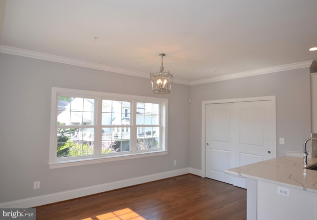 unfurnished dining area with dark hardwood / wood-style floors, ornamental molding, sink, and a chandelier