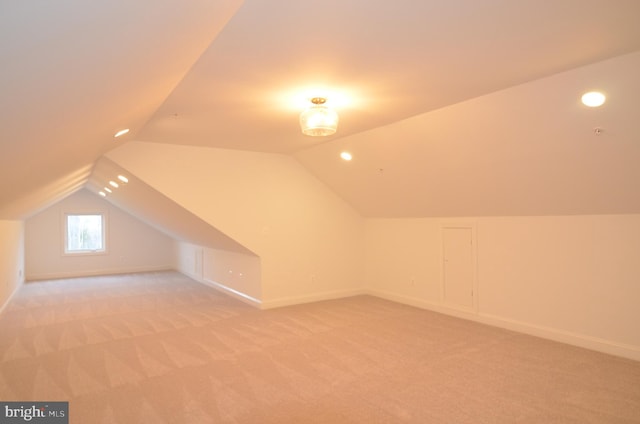 additional living space featuring light carpet and vaulted ceiling