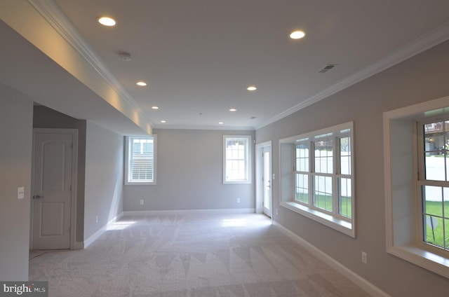 unfurnished room featuring crown molding, light colored carpet, and a wealth of natural light