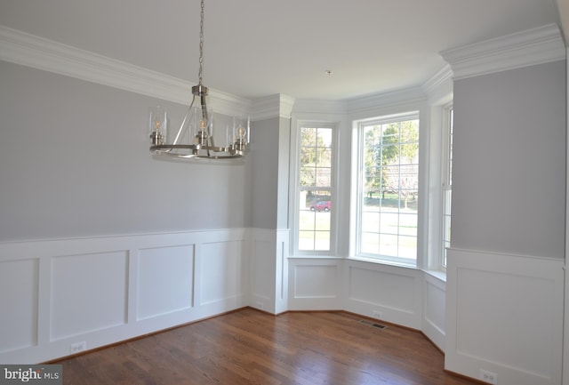 unfurnished dining area with a chandelier, plenty of natural light, dark hardwood / wood-style floors, and crown molding