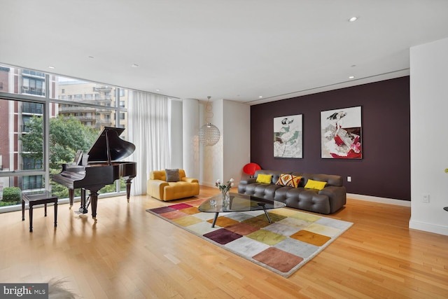 living room with wood finished floors, baseboards, recessed lighting, expansive windows, and an accent wall