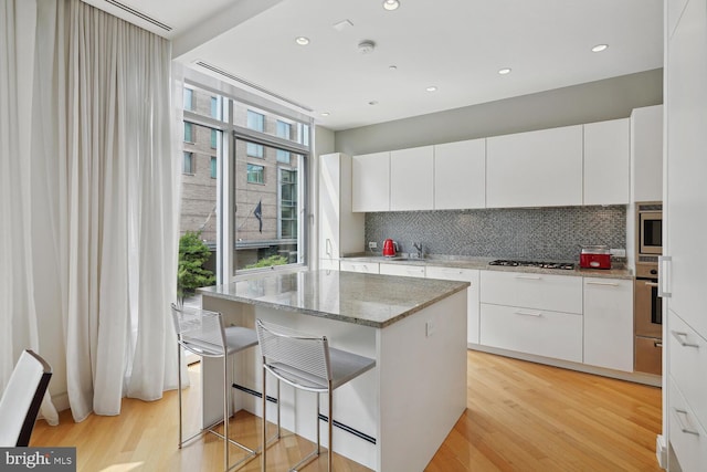 kitchen with light stone countertops, white cabinetry, plenty of natural light, and tasteful backsplash