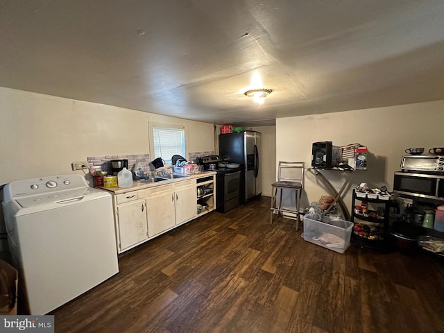 kitchen with appliances with stainless steel finishes, washer / dryer, dark wood-type flooring, and sink