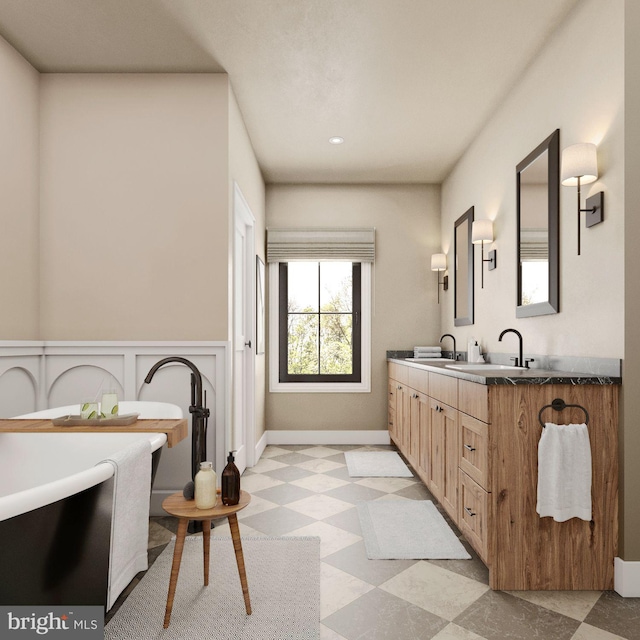 full bathroom with a freestanding tub, a sink, baseboards, tile patterned floors, and double vanity