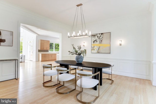 dining room with an inviting chandelier, crown molding, and light hardwood / wood-style flooring