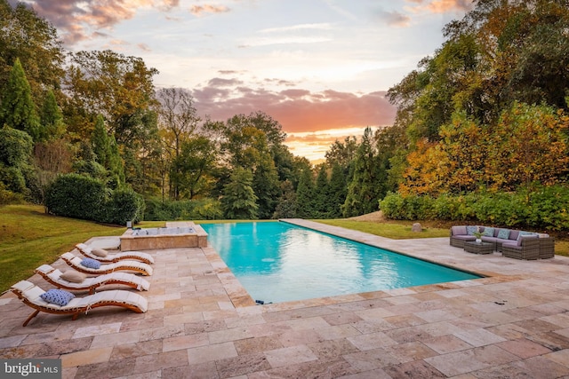 pool at dusk with an outdoor living space, a yard, and a patio