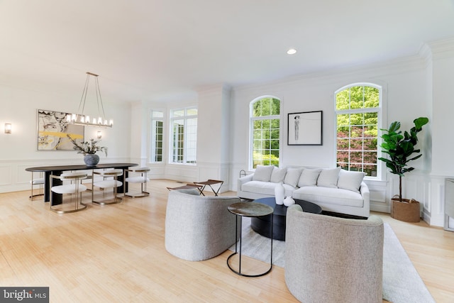 living room featuring a chandelier, crown molding, and light wood-type flooring