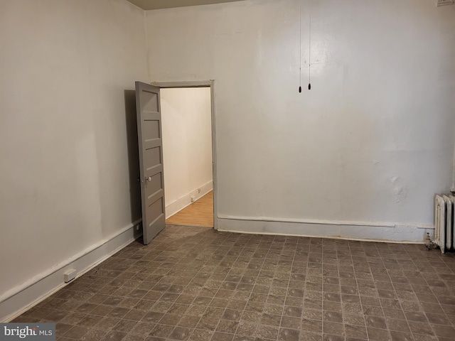 empty room with dark tile flooring and radiator