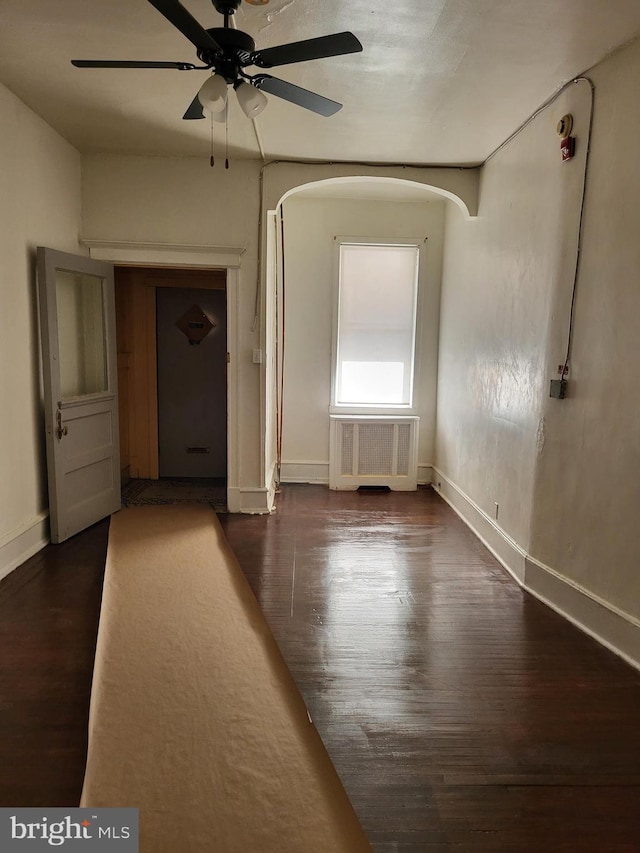 interior space with dark hardwood / wood-style floors, ceiling fan, and radiator heating unit