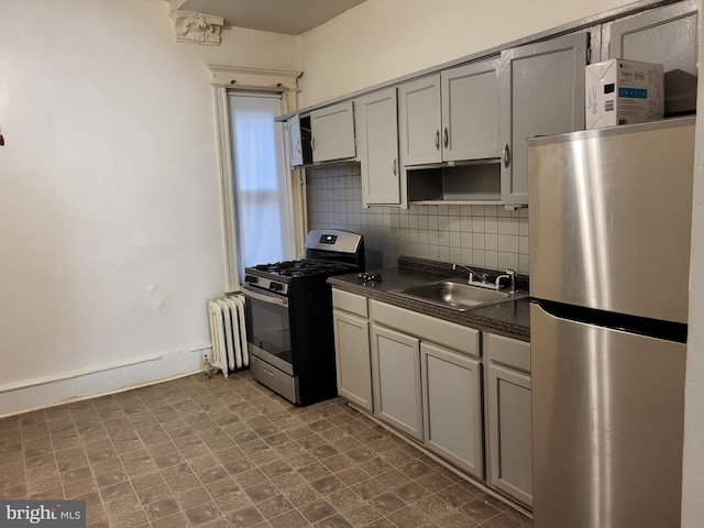 kitchen featuring backsplash, appliances with stainless steel finishes, sink, dark tile flooring, and radiator