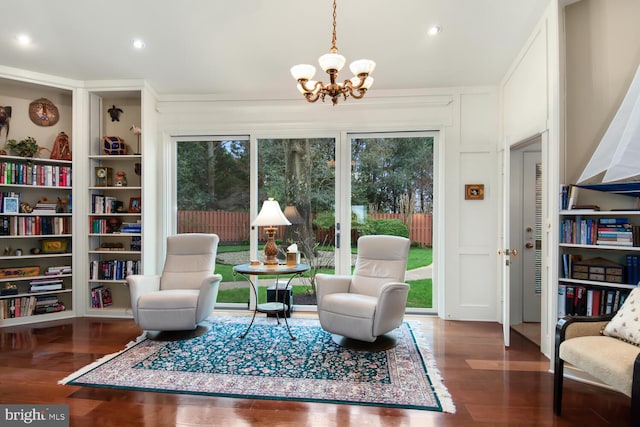 living area with an inviting chandelier, built in features, wood finished floors, and a wealth of natural light