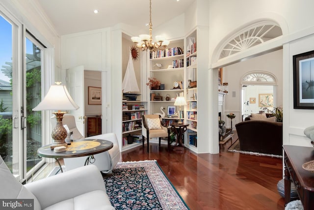 sitting room featuring a notable chandelier, built in shelves, and wood finished floors