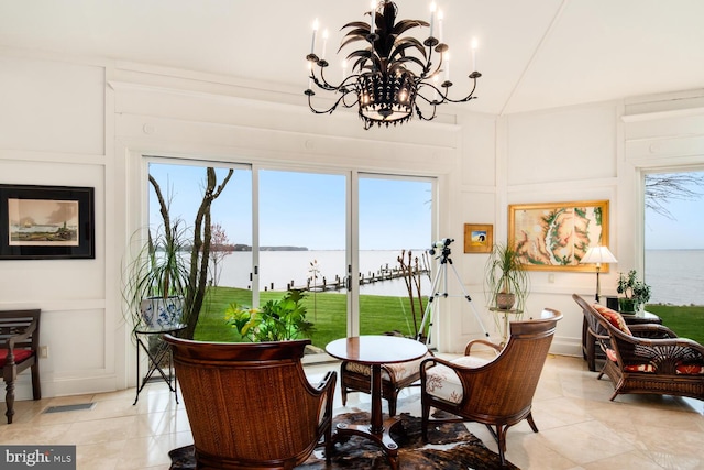 dining space with light tile patterned floors, a water view, and a decorative wall