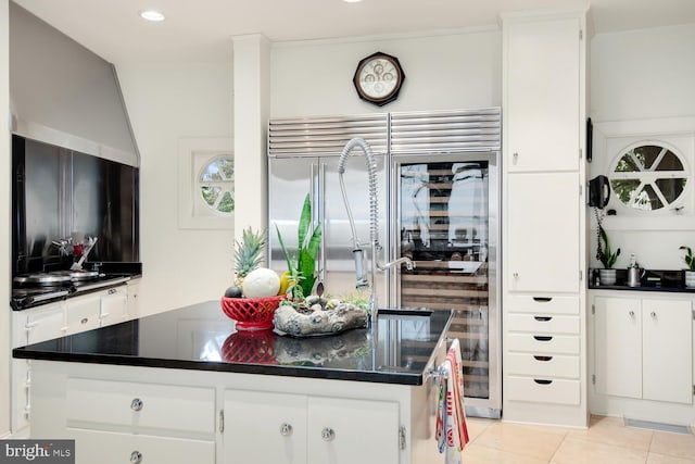 kitchen featuring light tile patterned floors, dark countertops, and white cabinetry