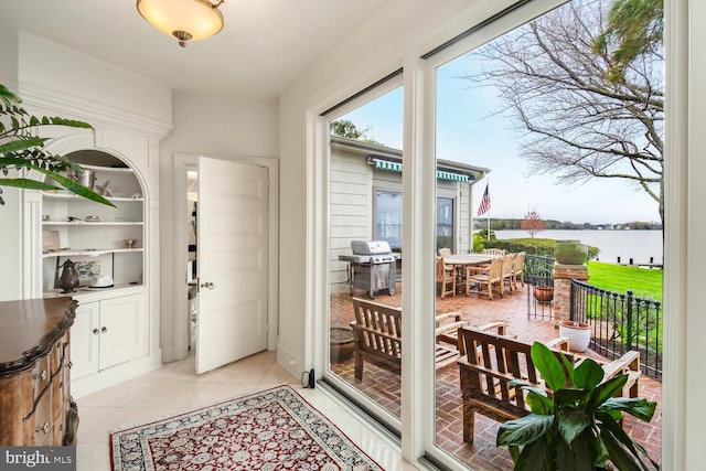 entryway with light tile patterned floors and a water view