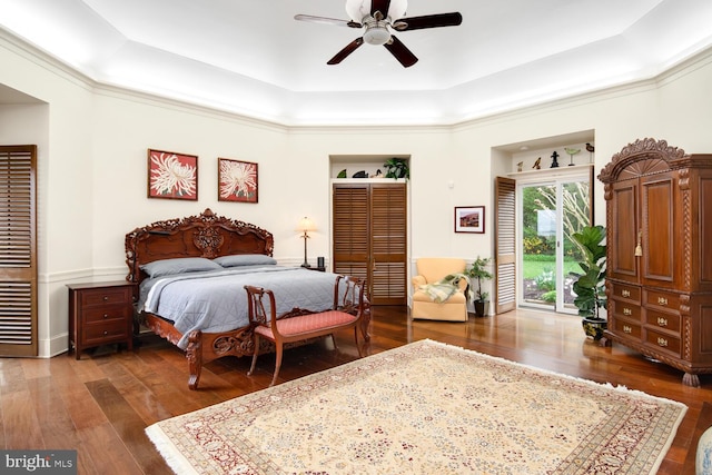 bedroom featuring a tray ceiling, access to outside, ceiling fan, and hardwood / wood-style flooring