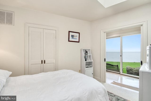 bedroom with visible vents, a water view, access to outside, a closet, and carpet floors