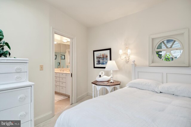 bedroom with ensuite bath, light colored carpet, baseboards, and a sink