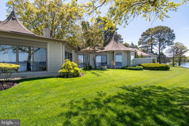 back of house featuring a lawn and a chimney