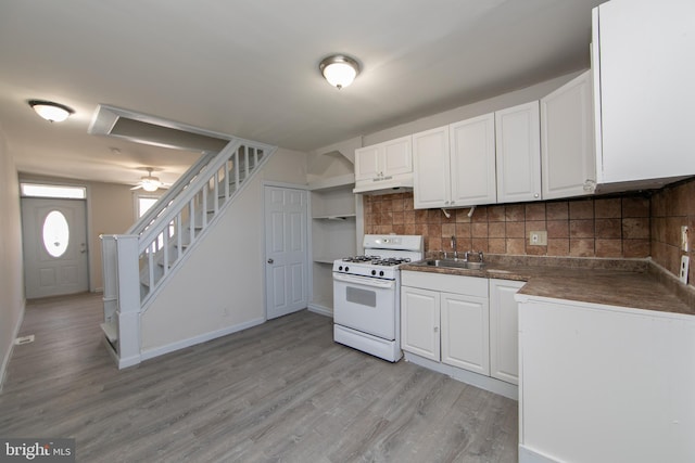 kitchen with white cabinetry, white range with gas cooktop, backsplash, ceiling fan, and light hardwood / wood-style flooring