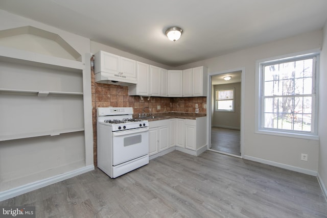 kitchen with gas range gas stove, backsplash, white cabinetry, and light wood-type flooring