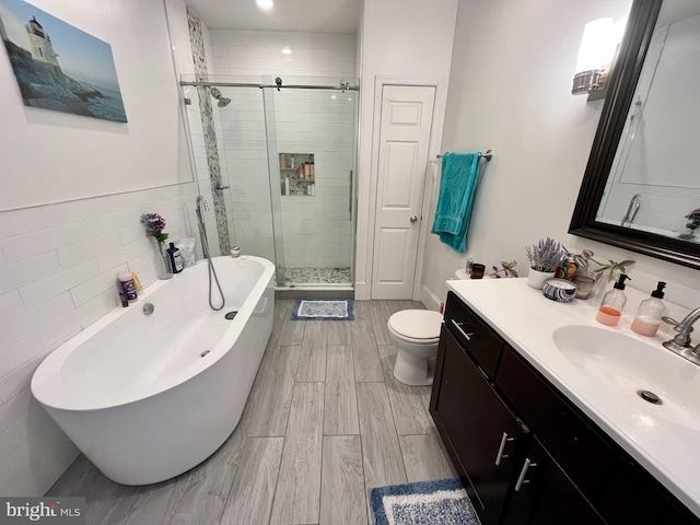 full bathroom with tile walls, vanity, plus walk in shower, and toilet