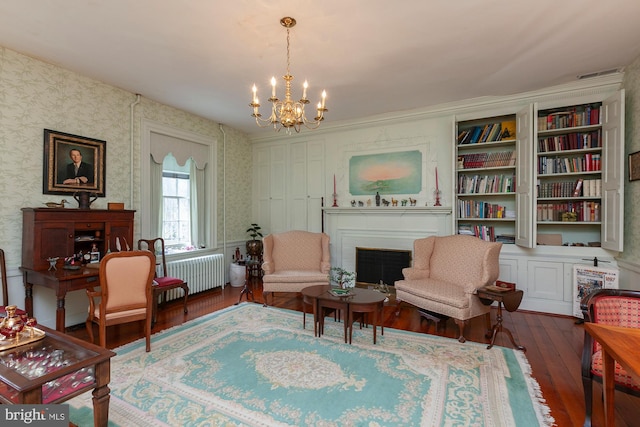 sitting room featuring dark hardwood / wood-style floors, built in shelves, radiator, and a chandelier