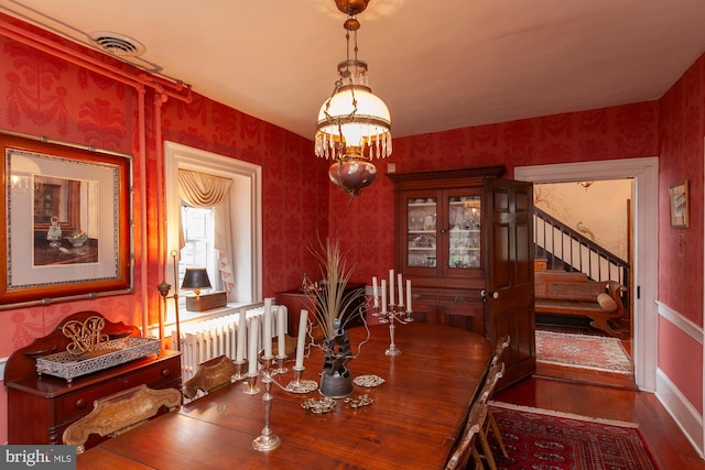 dining room with radiator, a chandelier, and dark hardwood / wood-style floors