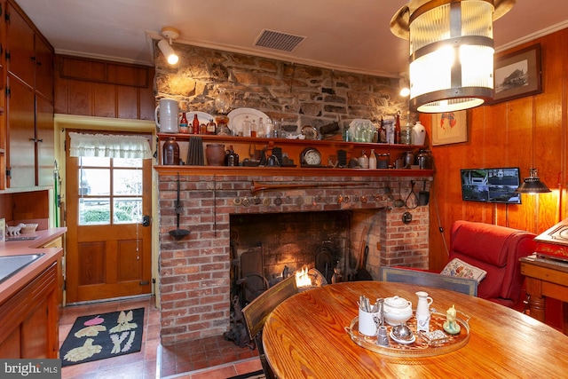 dining space featuring ornamental molding, a fireplace, and wooden walls