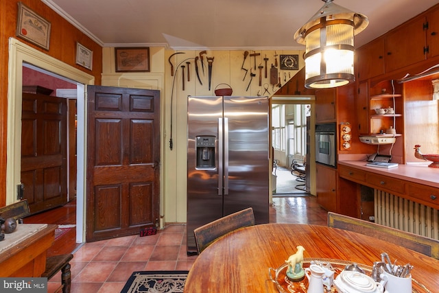 kitchen with appliances with stainless steel finishes, ornamental molding, and light tile patterned flooring