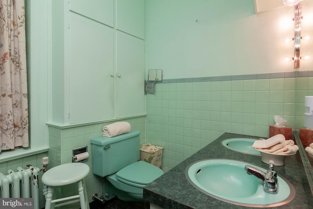 bathroom featuring vanity, toilet, radiator, and tile walls