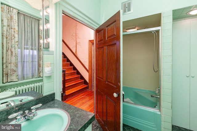 bathroom with hardwood / wood-style floors, vanity, enclosed tub / shower combo, and radiator heating unit