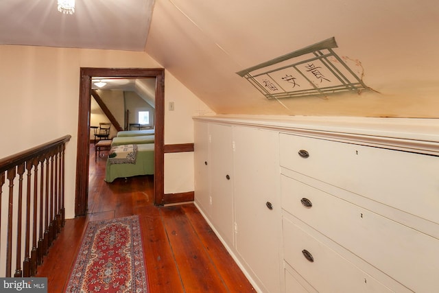 corridor with dark hardwood / wood-style floors and vaulted ceiling