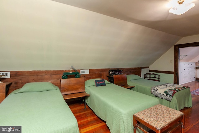 bedroom featuring dark hardwood / wood-style floors, lofted ceiling, and wooden walls