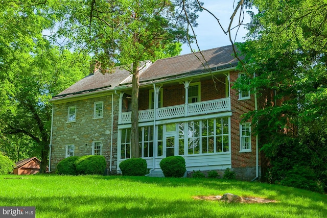 rear view of property featuring a balcony and a lawn