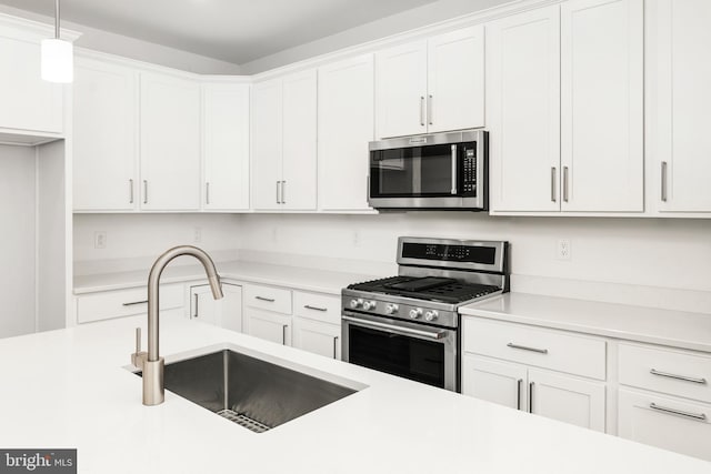 kitchen featuring pendant lighting, white cabinetry, sink, and stainless steel appliances