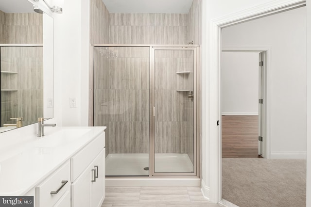 bathroom featuring walk in shower, hardwood / wood-style flooring, and vanity