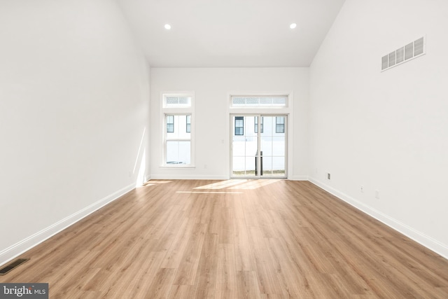 empty room featuring light hardwood / wood-style flooring and a high ceiling