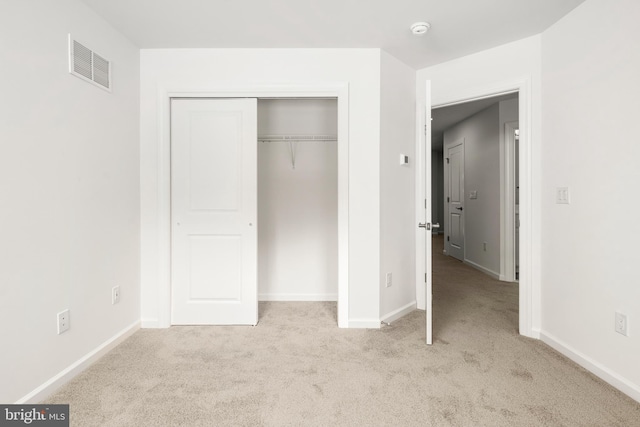 unfurnished bedroom with light colored carpet and a closet