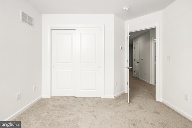 unfurnished bedroom with a closet and light colored carpet