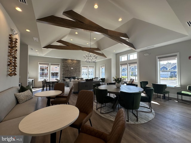 dining space featuring hardwood / wood-style flooring, a healthy amount of sunlight, high vaulted ceiling, and a chandelier