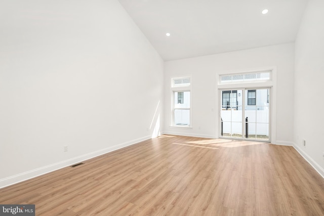 empty room featuring light hardwood / wood-style flooring and high vaulted ceiling