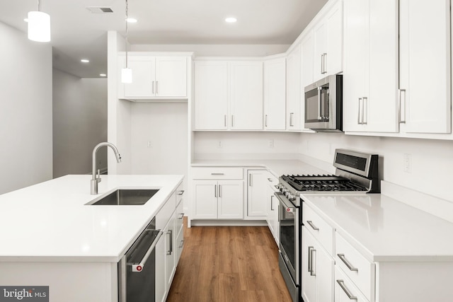 kitchen featuring white cabinets, hanging light fixtures, sink, appliances with stainless steel finishes, and dark hardwood / wood-style flooring