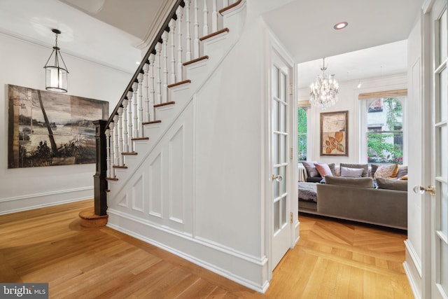 stairs featuring light parquet floors and an inviting chandelier