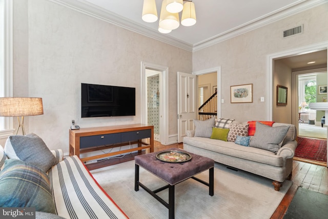 living room with hardwood / wood-style flooring, ornamental molding, an inviting chandelier, and radiator heating unit